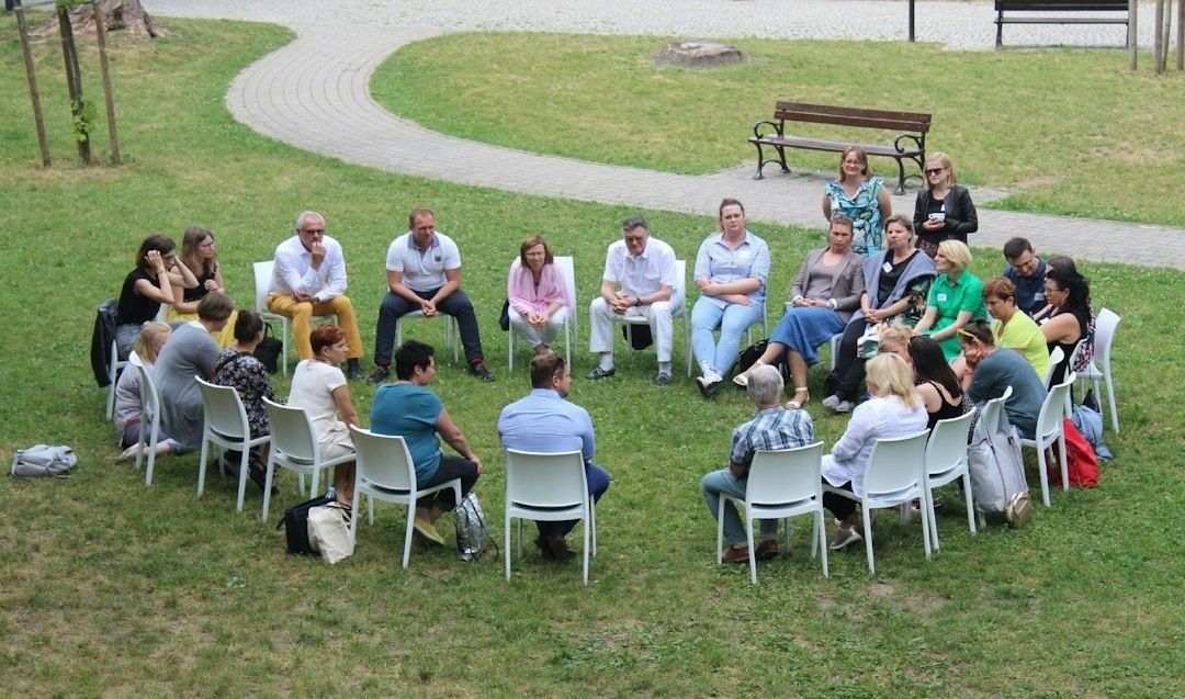 Grupp människor sitter i en ring och samtalar på en gräsmatta