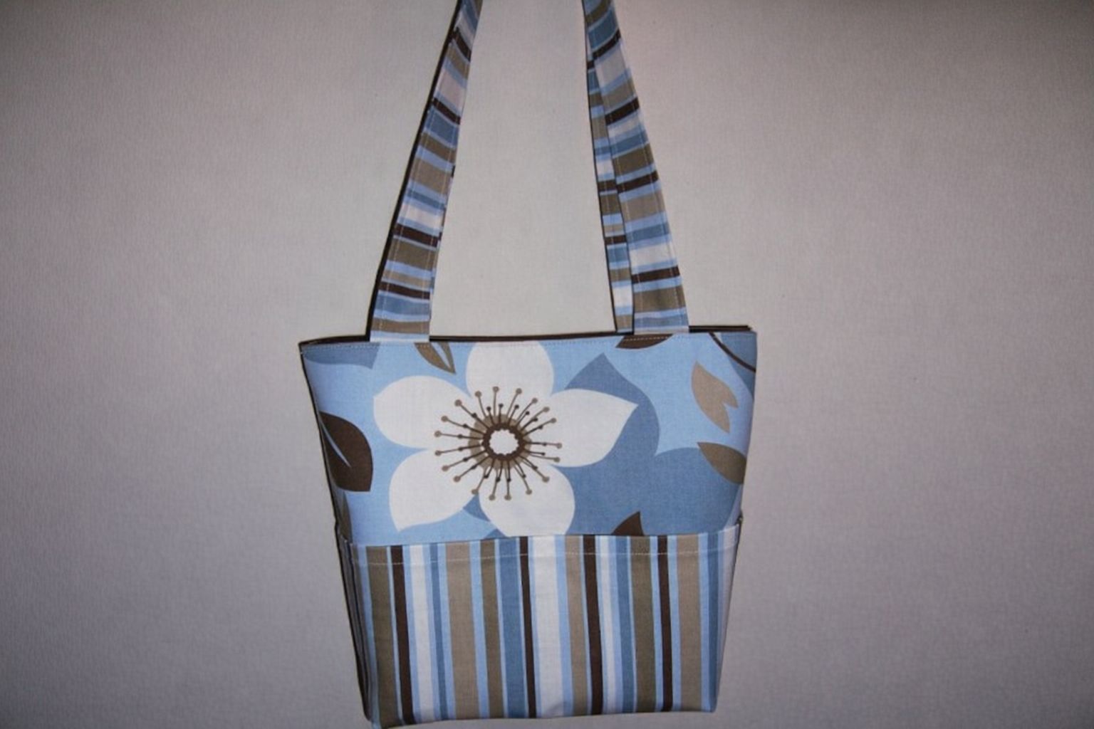 En tygpåse med blommigt och randigt mönster i blått, vitt, brunt och beige.